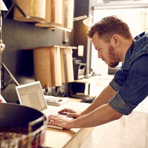 Business owner of a coffee roastery checking his laptop Small business owner of roastery checking his laptop